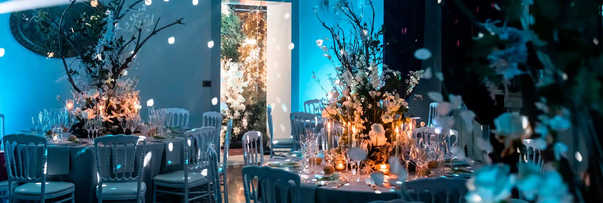 Elegante decorazione per matrimonio, tavoli allestiti con fiori bianchi e candele, atmosfera romantica con illuminazione soffusa, perfetta per eventi wedding di lusso.