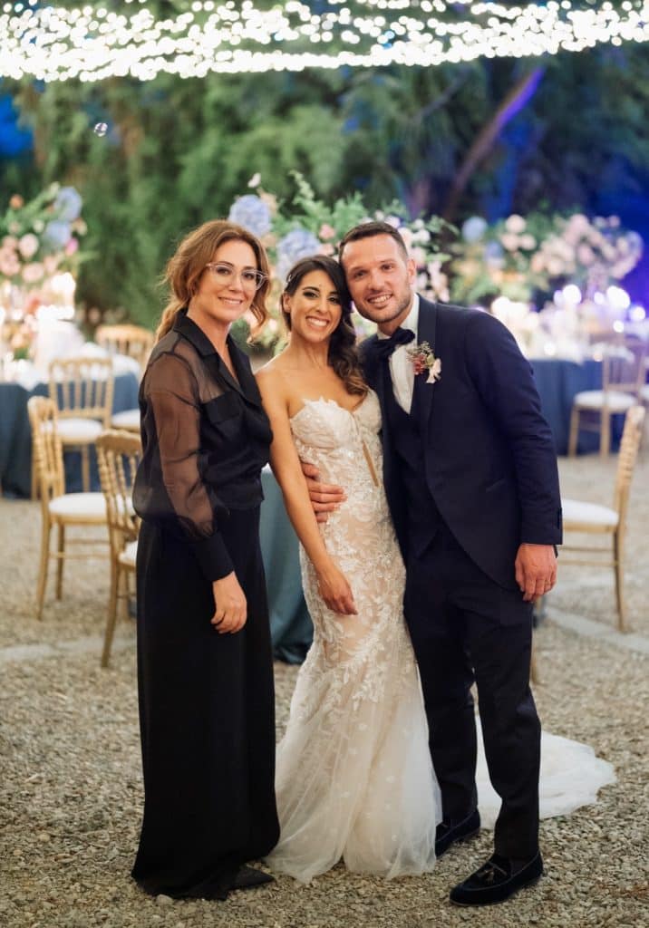 Elegant wedding celebration organized by ChiaraB Events, featuring a happy bride and groom with a wedding planner, outdoor setting, floral arrangements, and sophisticated decor.