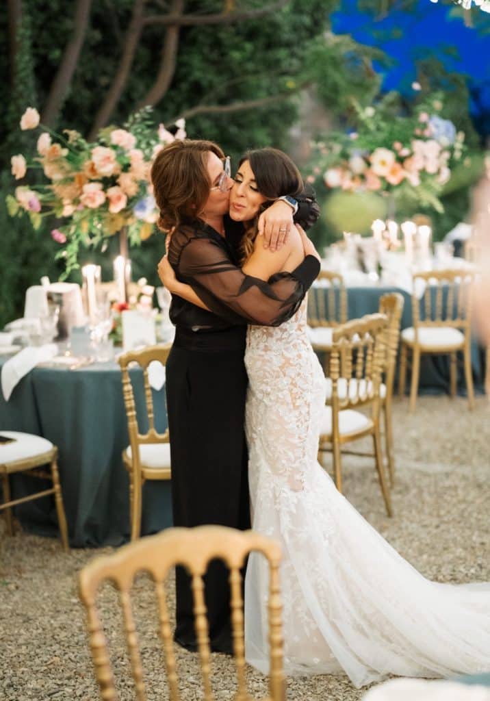 Bacio tra sposa e assistente, evento matrimonio elegante con decorazioni floreali e Tavoli raffinati, servizi di wedding planner professionale ChiaraB Events in ambiente outdoor.