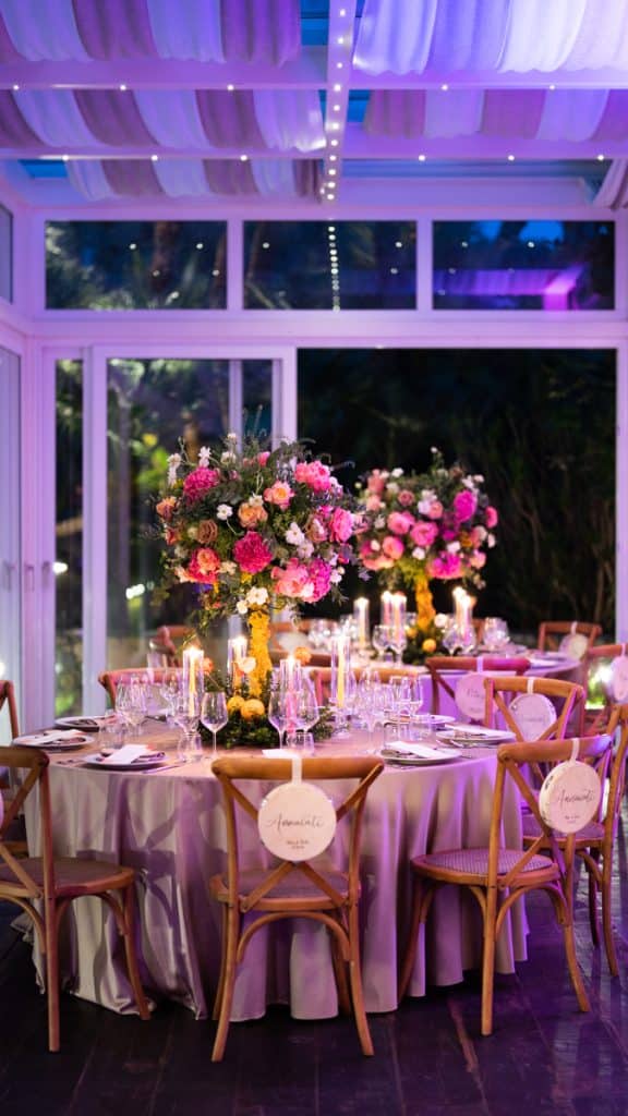 Fotoritratto di un'elegante tavola di matrimonio decorata con splendidi centrotavola floreali rosa e sfumature di bianco, illuminata da candele, perfetta per eventi e matrimoni.