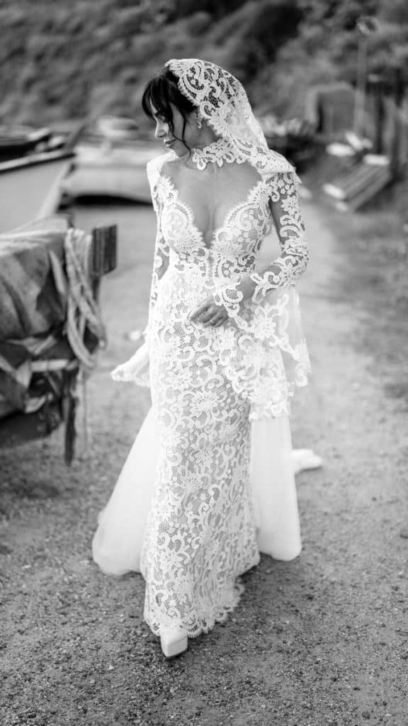 Elegante abito da sposa in pizzo con mantellina, style boho chic, perfetto per matrimoni all'aperto e cerimonie sofisticate.