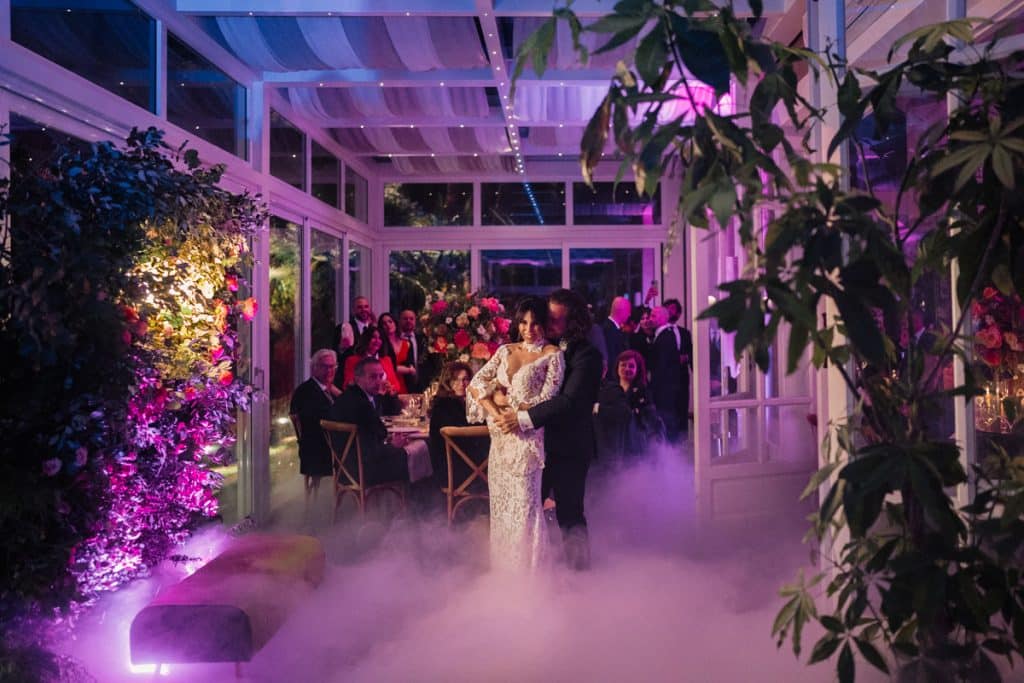 Elegante coppia di sposi che balla durante un matrimonio in una sala luminosa e decorata con luci soffuse, fiori freschi e atmosfere magiche, organizzato da ChiaraB Events, wedding planner professionista.