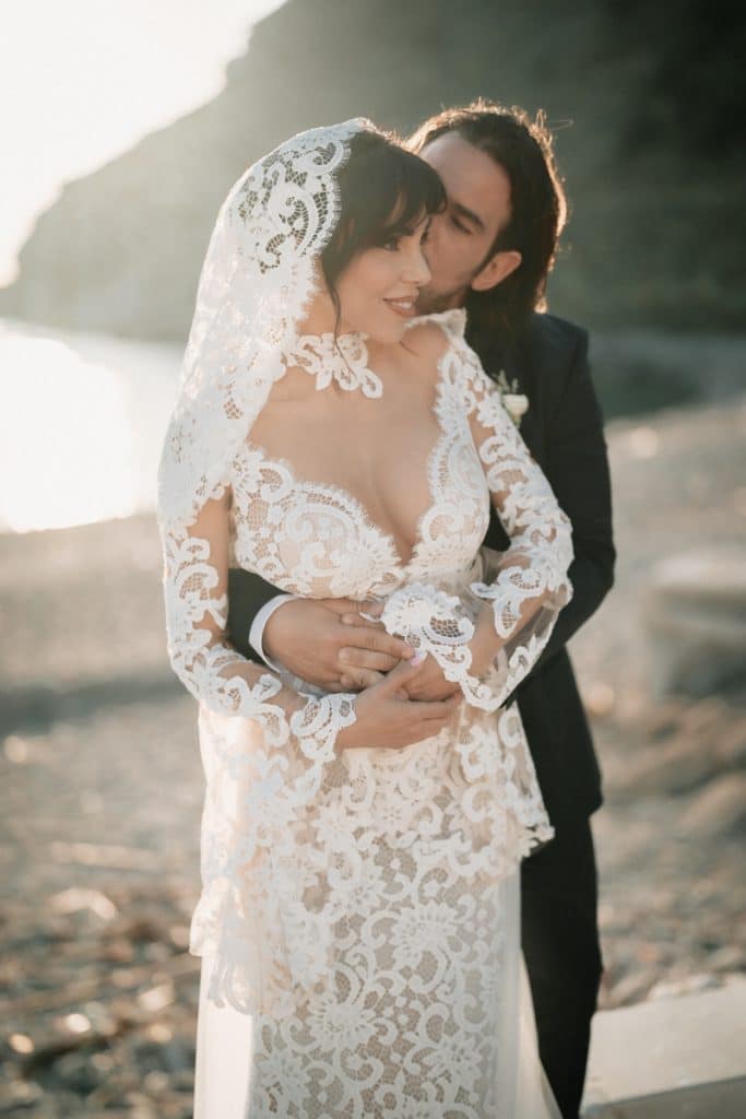 Parte superiore del corpo di una coppia di sposi in abiti da matrimonio sulla spiaggia al tramonto, stile romantico, dettagli estetici eleganti, servizi per matrimoni, pianificazione dettagliata.
