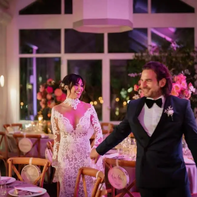 Beautiful bride and groom in a'cosy wedding hall decorated with elegant pink flowers and a romantic setting, perfect for a top wedding planner.