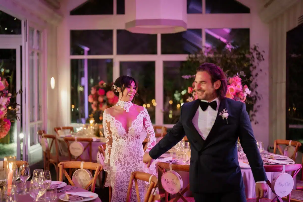 Bellissima coppia di sposi in un'accogliente sala da matrimonio decorata con eleganti fiori rosa e ambientazione romantica, perfetta per un wedding planner di alto livello.