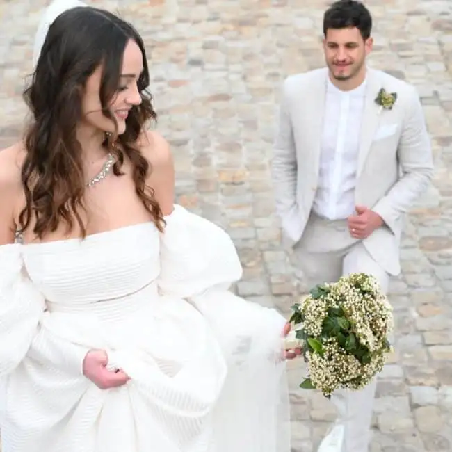 Fotografia di un matrimonio con una coppia felice, sposa in abito bianco e fiore tra le mani, matrimonio elegante, servizi di wedding planning, ChiaraB Events Wedding Planner, location romantica, evento nuziale di lusso.