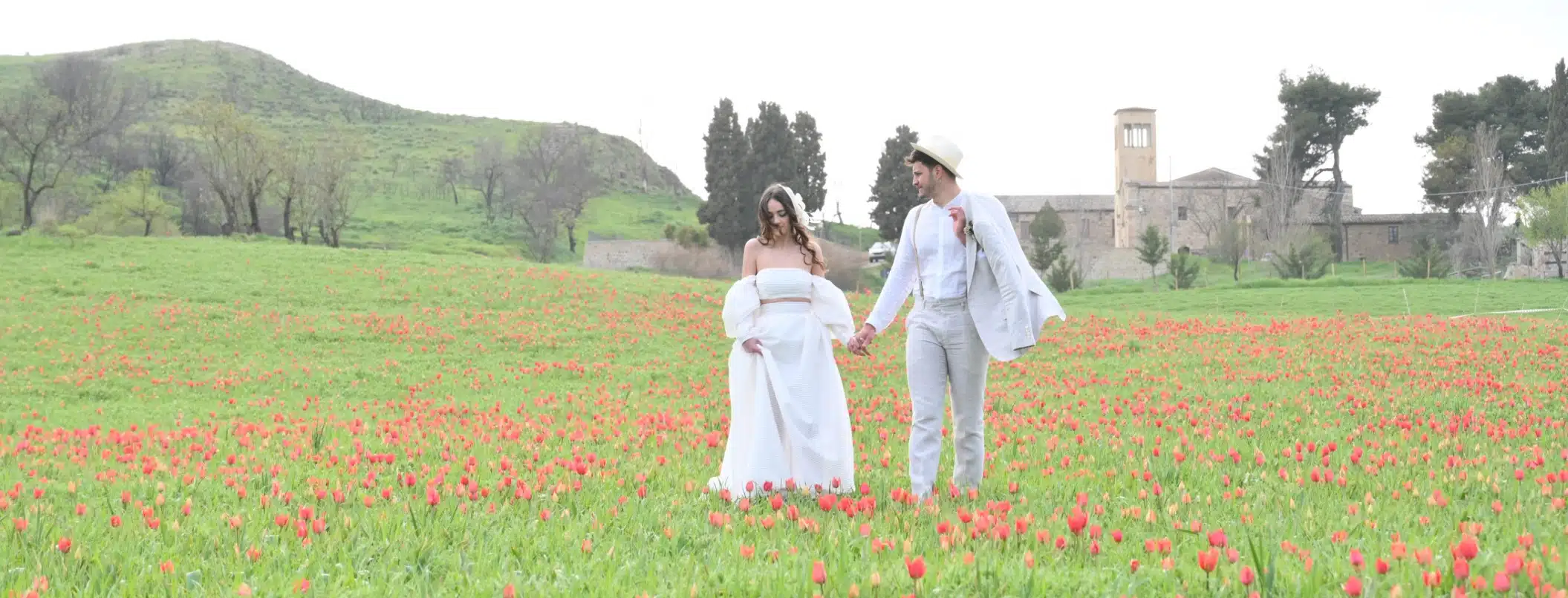Fiorista matrimonio in campagna con coppia in abiti eleganti, scena romantica all'aperto con natura e paesaggio rurale.