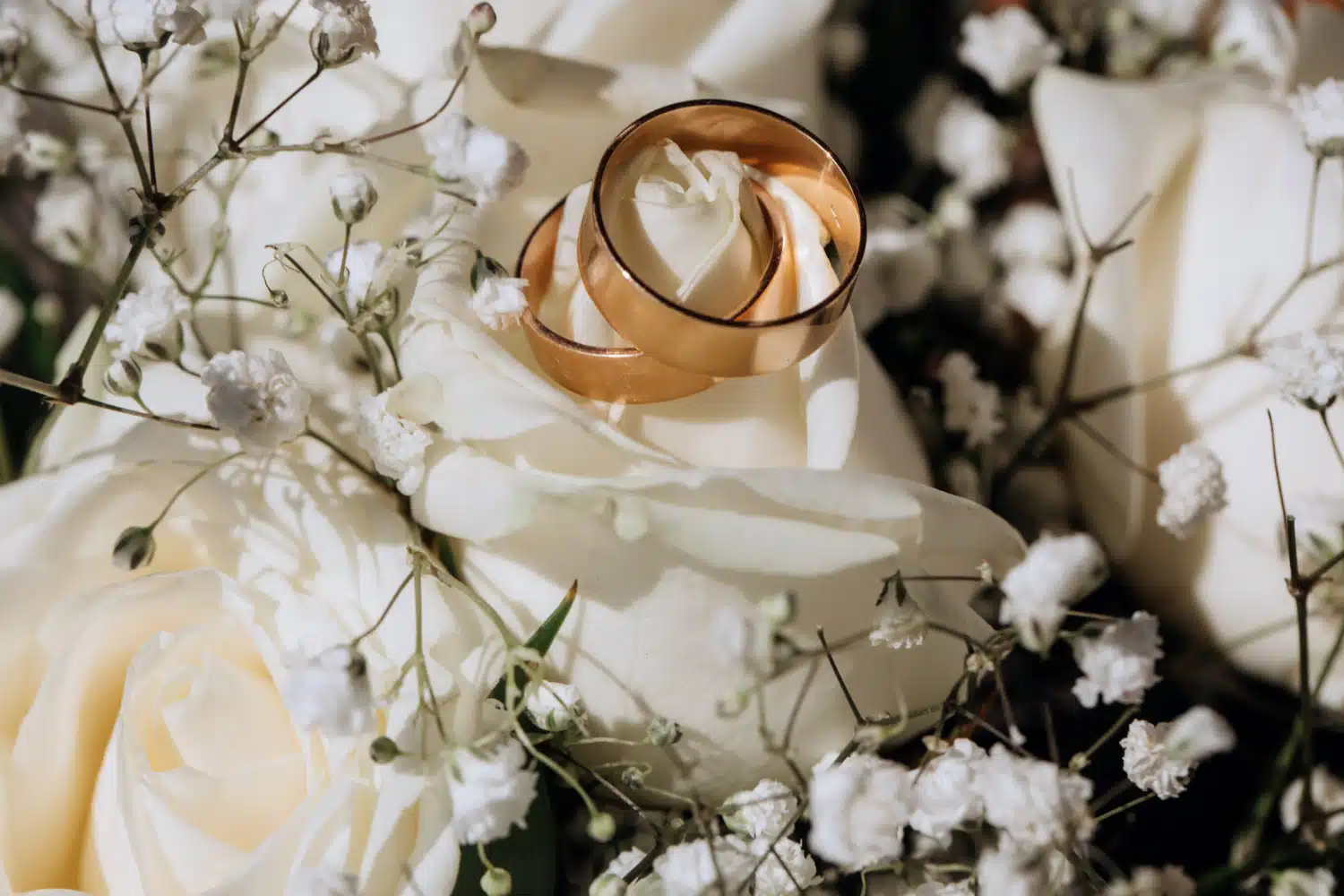 Anelli nuziali posati su fiori bianchi, decorazione elegante e raffinata per matrimoni, wedding planner chiaraB events, servizio di pianificazione nozze di lusso, atmosfera romantica, dettagli curati.
