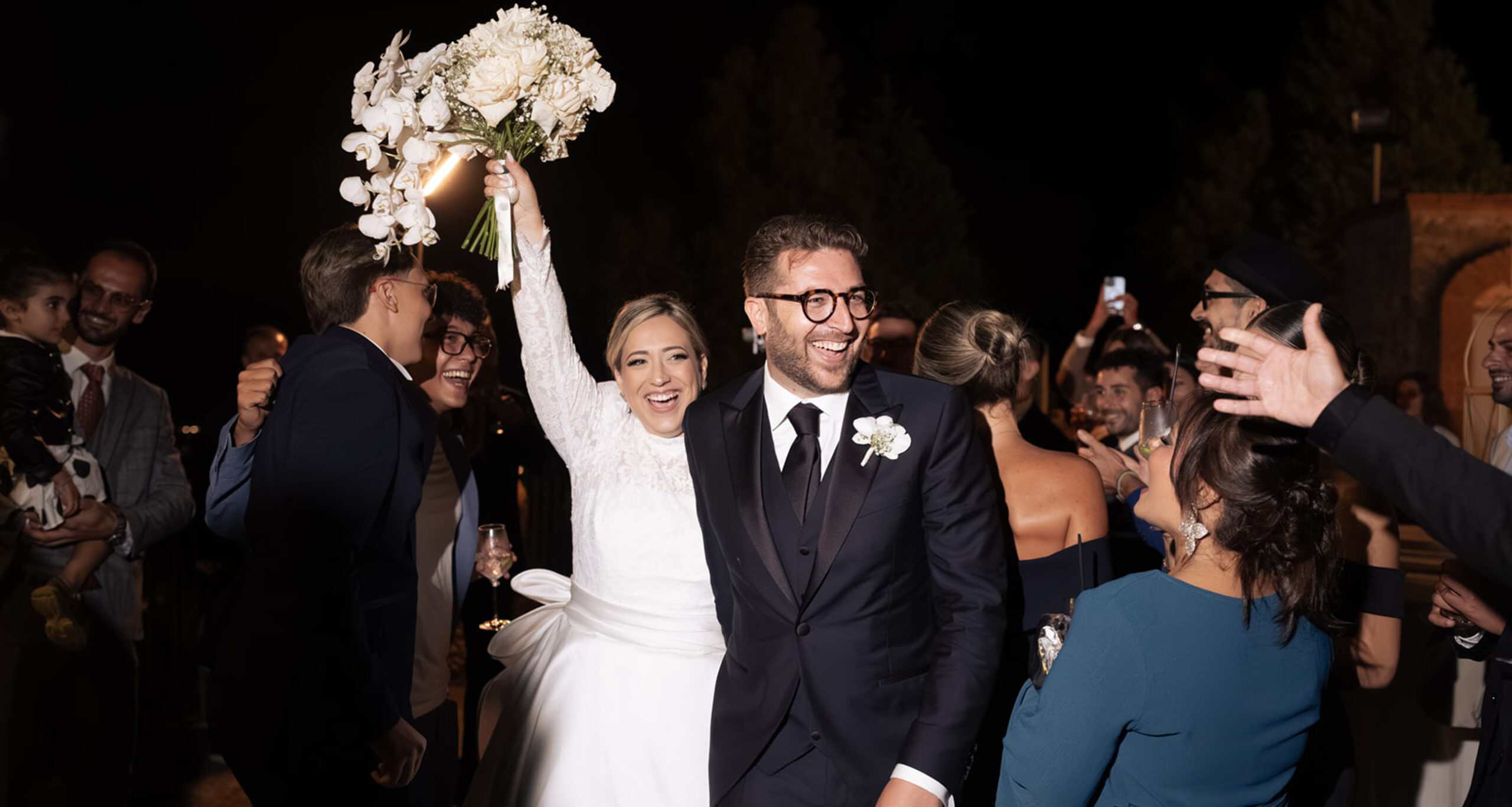 Sposi felici durante il ricevimento di nozze con amici e familiari, celebrando un matrimonio elegante e gioioso.