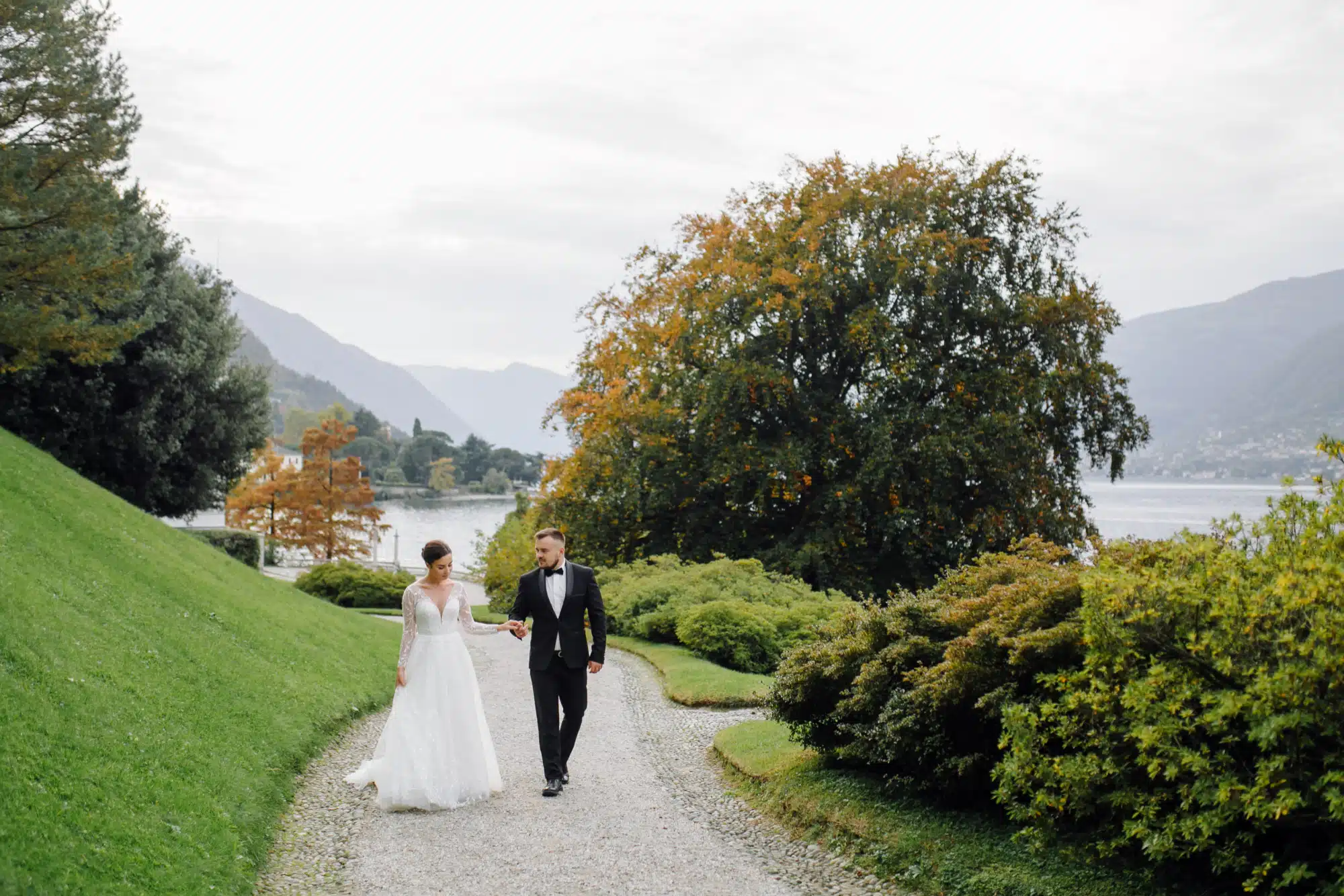 Elegante coppia di sposi che passeggia in un giardino, perfetta per servizi di wedding planning, matrimoni romantici e organizzazione eventi nuziali in location da sogno.