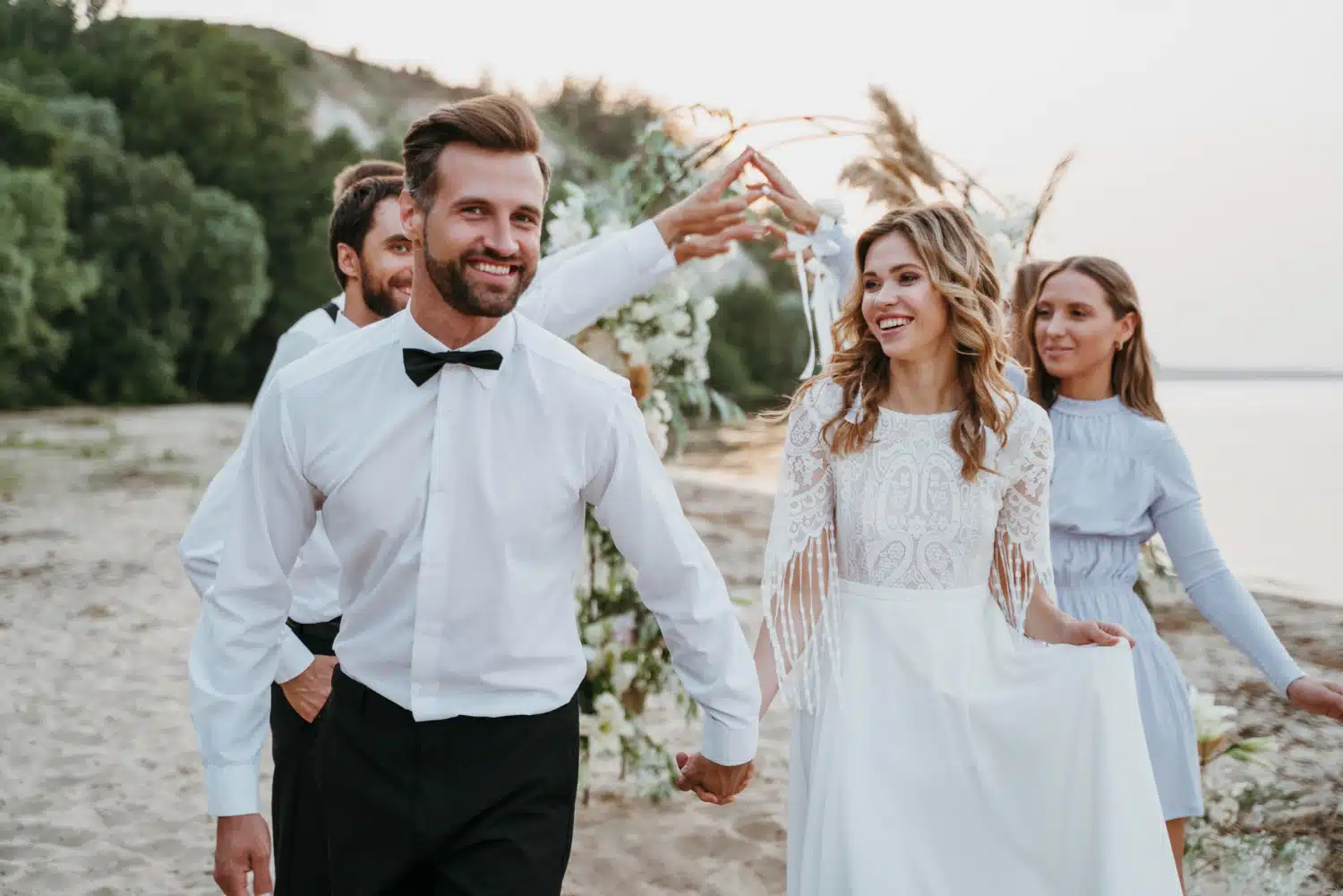 Donna e uomo felici al matrimonio in spiaggia con decorazioni floreali, matrimonio boho chic, wedding planner ChiaraB Events, cerimonia romantica all'aperto, fotografi di matrimoni e organizzazione eventi.