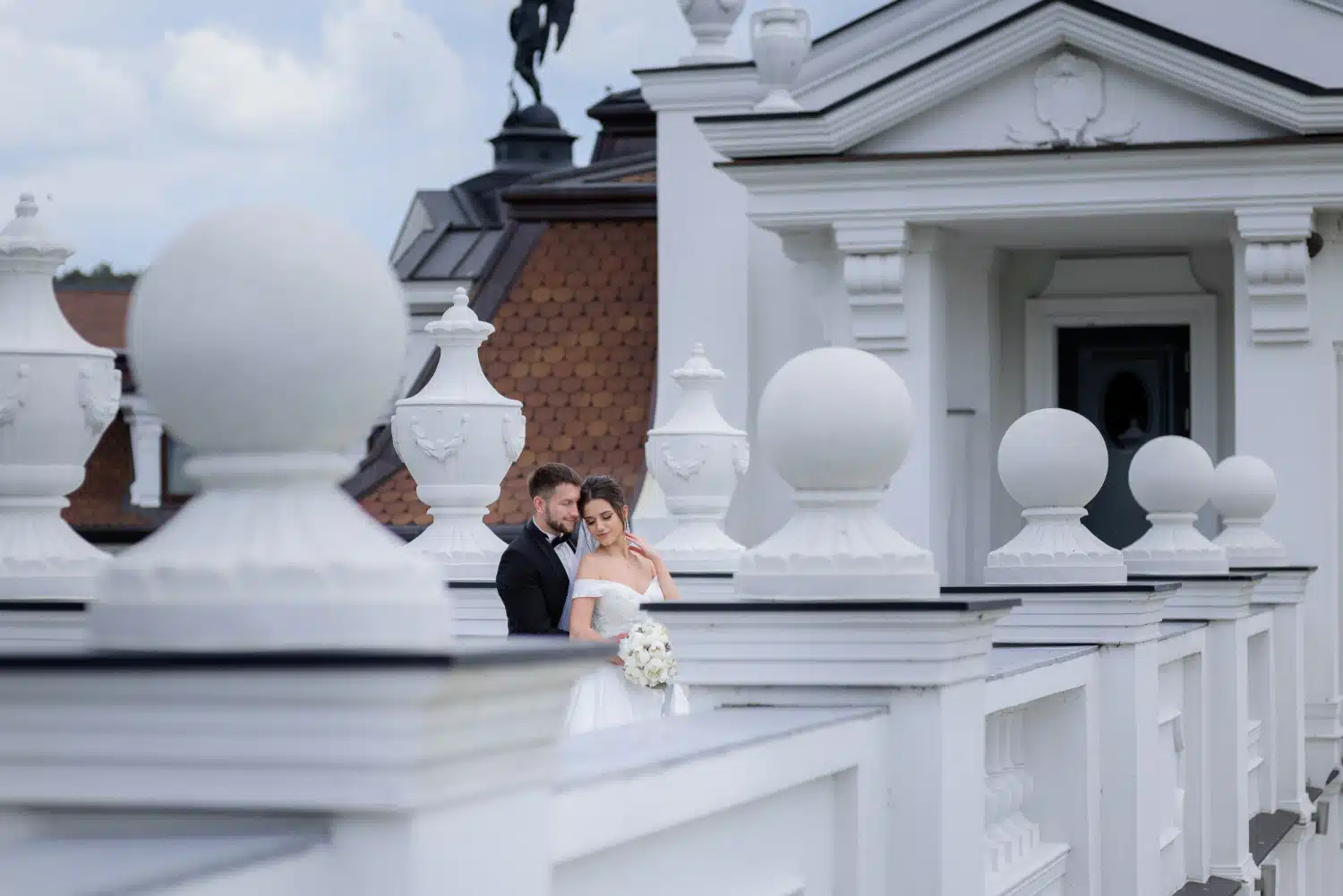 Elegant ægtepar på balkonen i en stor hvid bygning, romantisk bryllup, professionel bryllupsplanlægger, ChiaraB Events, ved hånden.