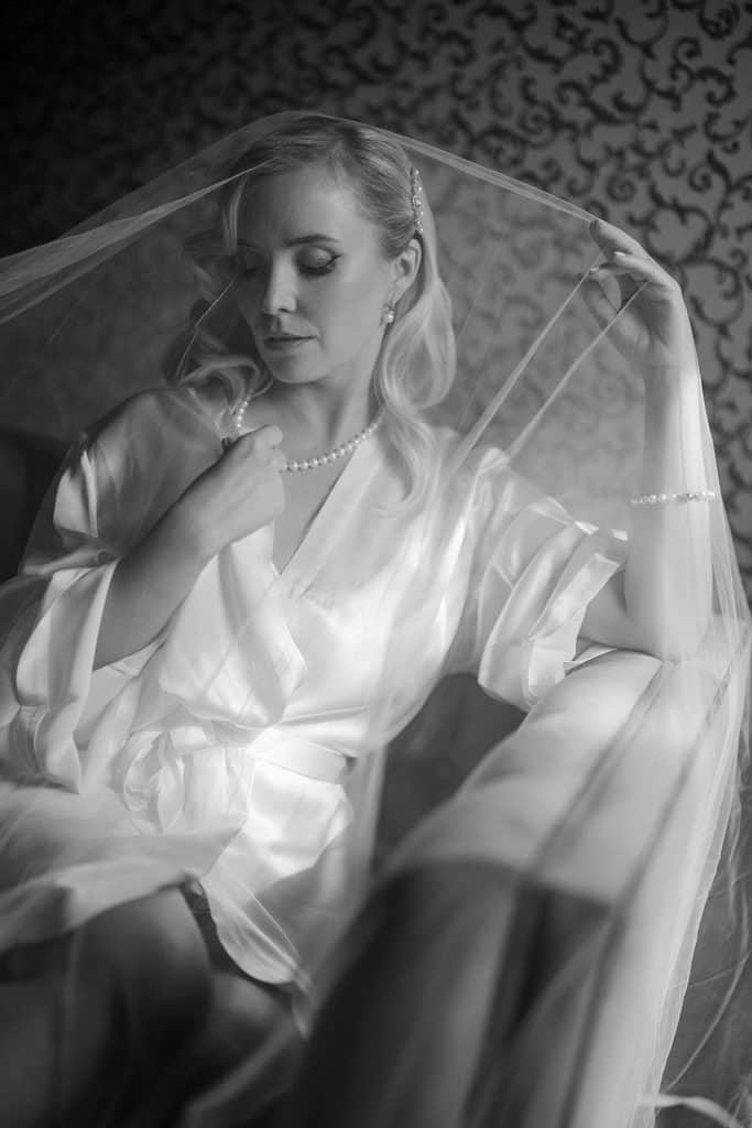 Elegante sposa con velo e abito di seta, pronta per il matrimonio, in un ambiente raffinato e sofisticato, perfetto per servizi di wedding planning e organizzazione di matrimoni di lusso.