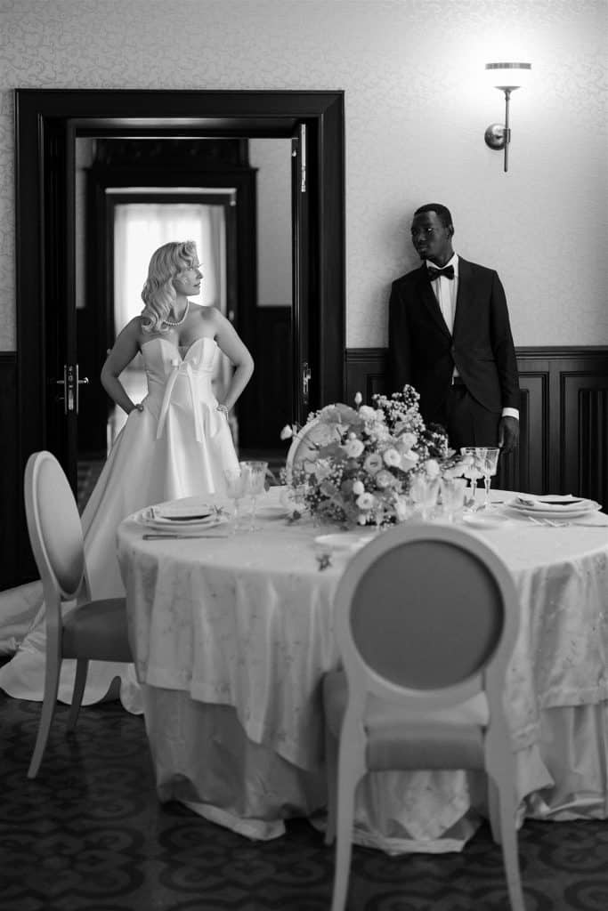 Elegante coppia di sposi in abiti da matrimonio, pronti per il loro ricevimento, decorazioni floreali e tavolo imbandito, in un ambiente raffinato e sofisticato, perfetto per matrimoni di classe.