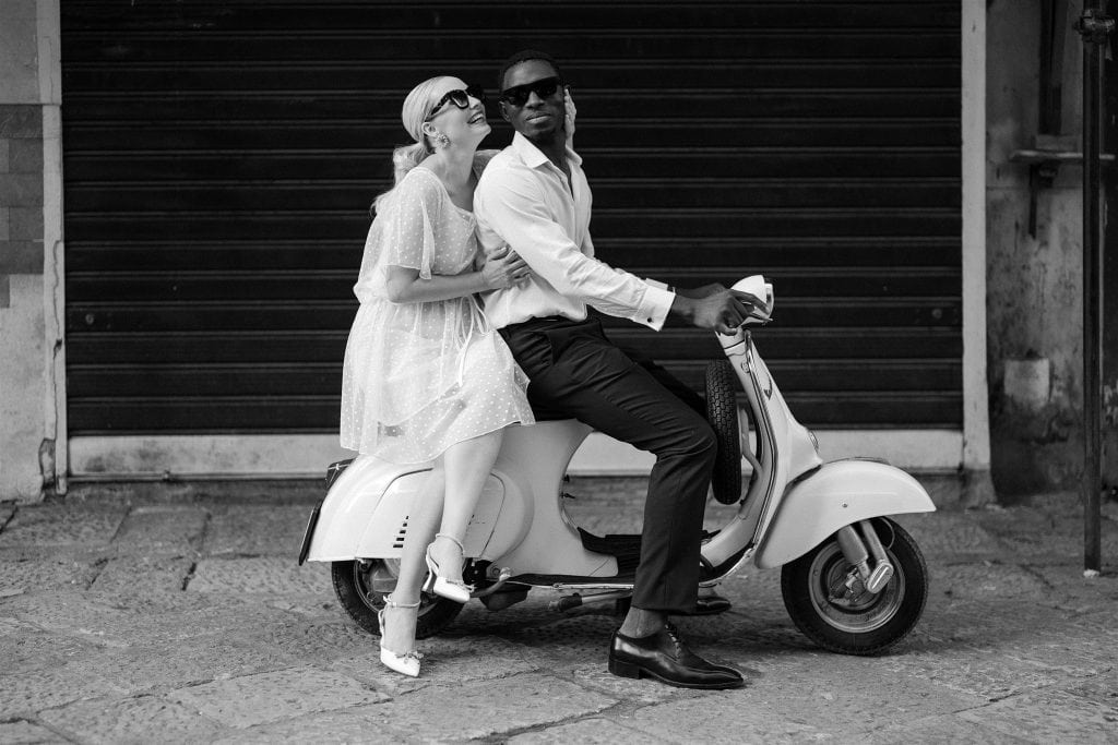 Vespa con coppia di sposi in stile vintage, in un'ambientazione urbana, perfetta per servizi fotografici di matrimoni e eventi romantici.