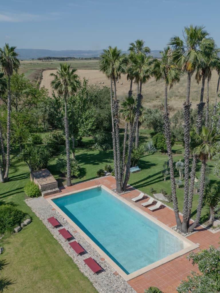 Outdoor pool with palm trees and relaxation area, ideal for weddings and outdoor events, in a natural and peaceful environment, perfect for celebrating special moments with style and elegance.