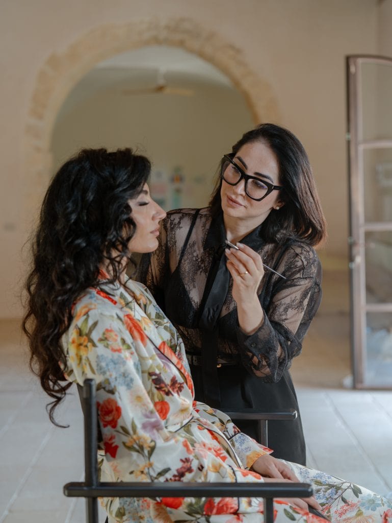A ChiaraB Events wedding assistant taking care of the bride during makeup, in an elegant and welcoming environment, with attention to detail and professionalism.