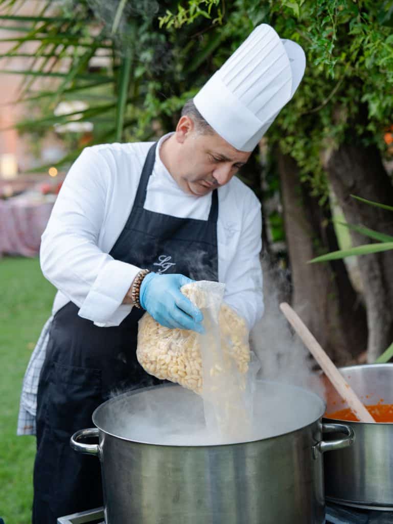 Fresh octopus cooking, professional chef in kitchen attire, outdoor kitchen with green plants in the background, catering service for events and weddings, ChiaraB Events Wedding Planner.