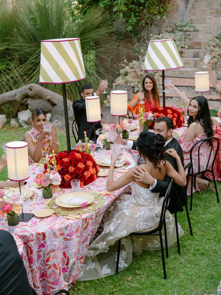 An illustration of an outdoor wedding with a table decorated with flowers and candles, guests toasting and festive atmosphere, perfect for wedding planning and event organization services.