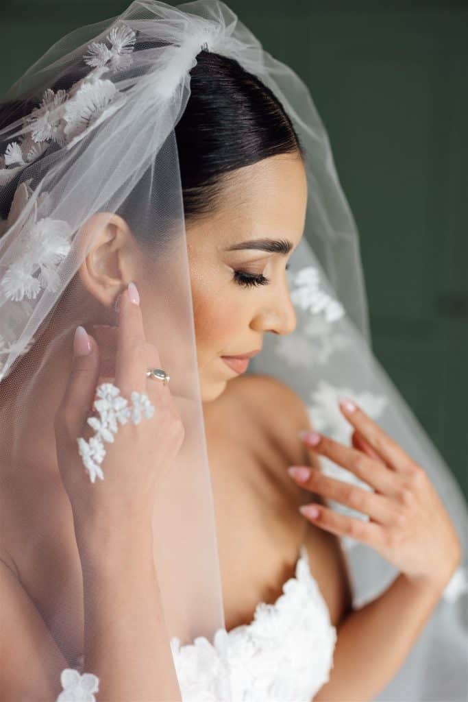 Sposa con velo e abito da matrimonio elegante, ritratta in un momento di contemplazione, con dettagli raffinati e trucco impeccabile, perfetta per servizi di wedding planning e organizzazione matrimon.
