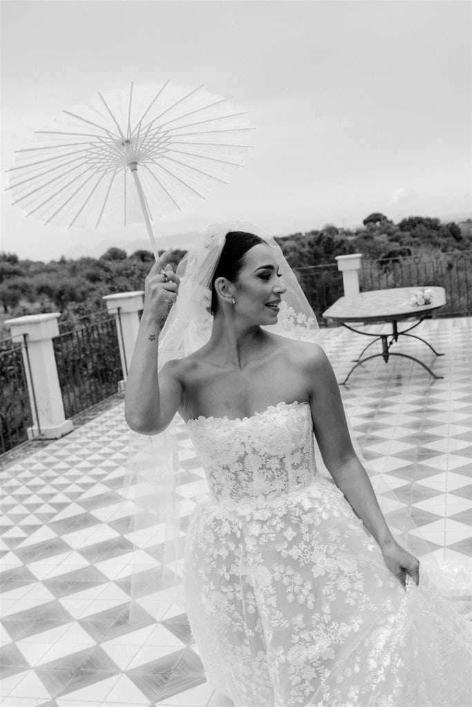 Parapluie bianco elegante con sposa sorridente in abito da matrimonio, vista panoramica all'aperto, perfetta per pianificazione matrimoni e servizi di wedding planning.