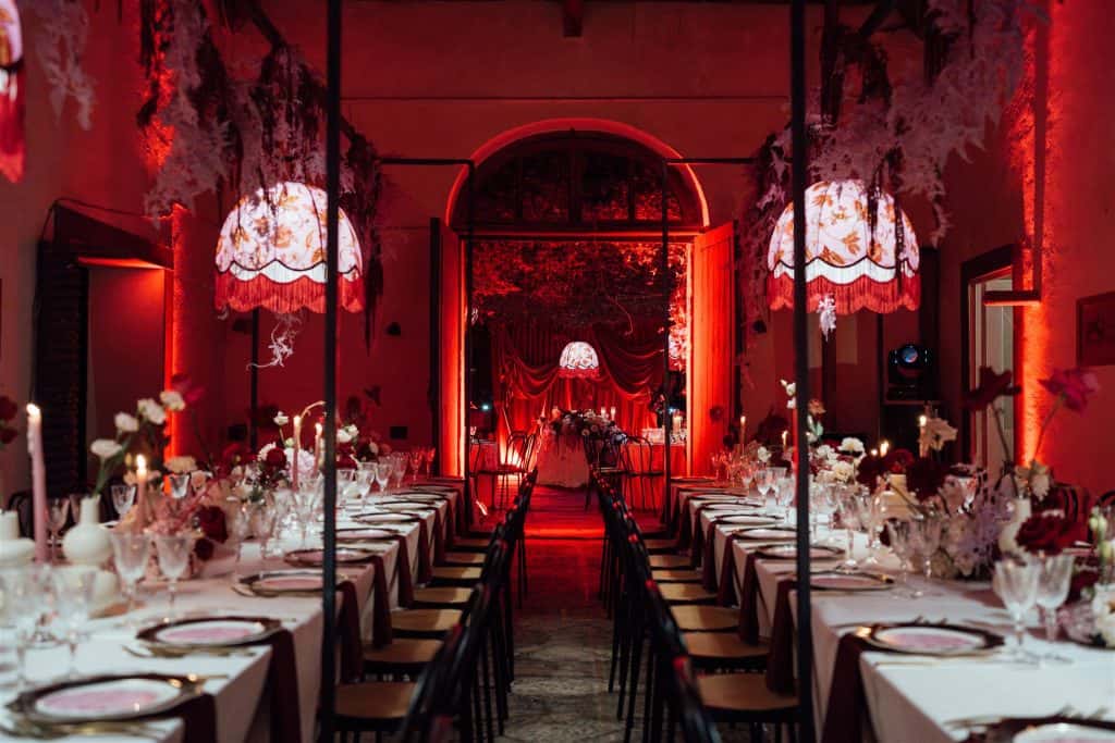 Sala per matrimonio decorata con luci rosse, tavoli eleganti e dettagli floreali, perfetta per un evento romantico e sofisticato come il matrimonio di Nico & Erica.