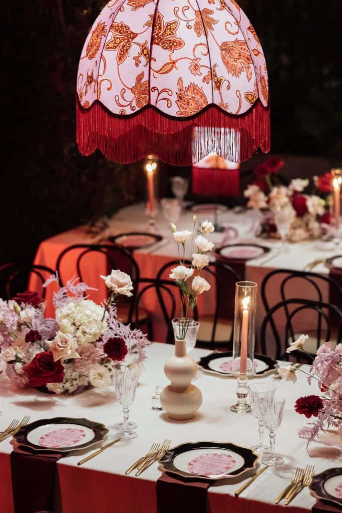 Luci soffuse e decorazioni floreali eleganti per un matrimonio romantico, con un lampadario vintage e tavoli decorati con fiori e candele, perfetti per un wedding planner professionale.
