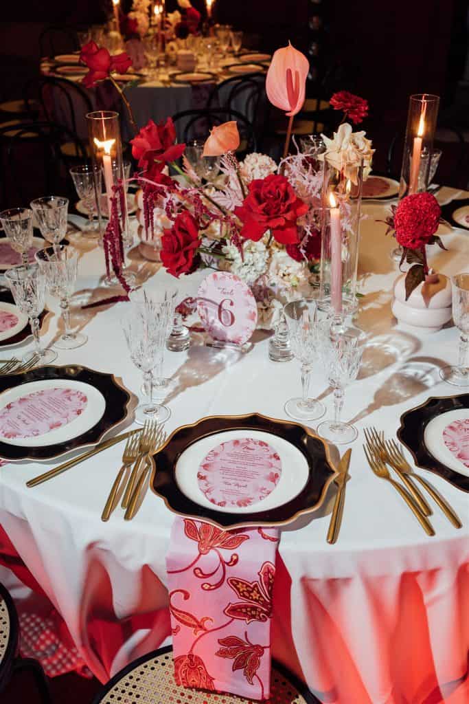 Tavola nuziale elegante decorata con fiori rossi e rosa, candele e dettagli raffinati, perfetta per un matrimonio romantico organizzato da ChiaraB Events Wedding Planner.