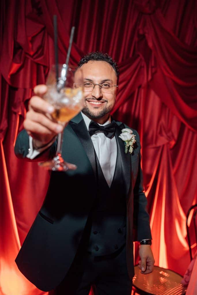 Tavolozza di colori caldi e atmosfera elegante con sposo sorridente che brinda durante il matrimonio, decorazioni di lusso e dettagli raffinati, perfetti per servizi di wedding planning di ChiaraB Eve.