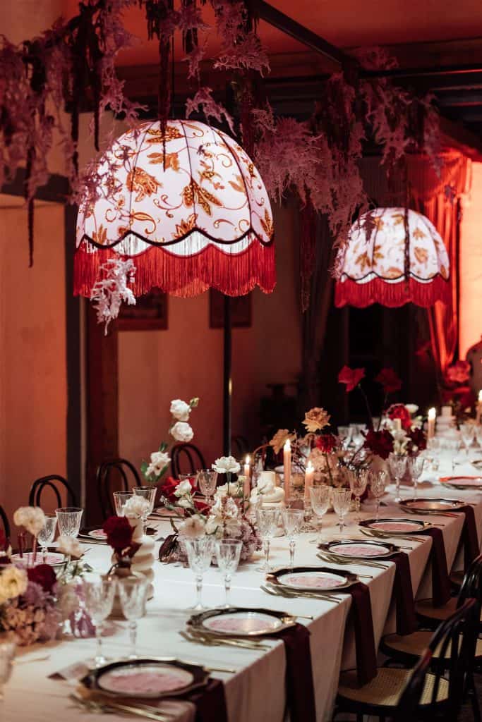 Decorazione elegante per matrimonio con lampade a sospensione floreali e tavolo imbandito con fiori e cristalli, perfetta per eventi romantici e sofisticati.