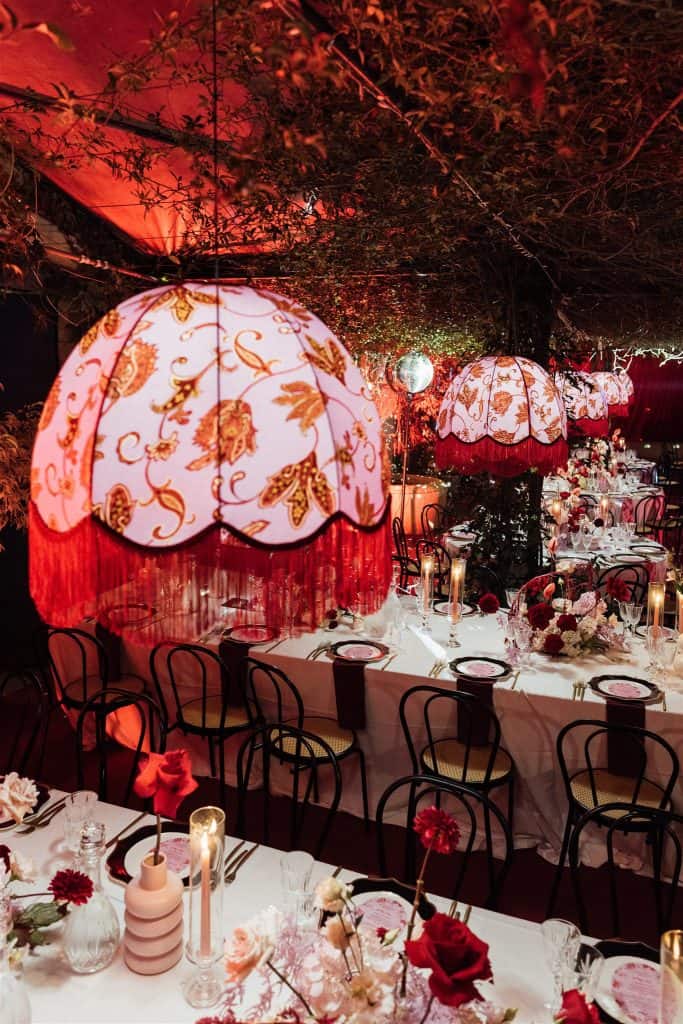 Lampada decorativa con paralume floreale e dettagli di pendenti rossi, illuminazione calda e romantica per un matrimonio elegante e raffinato.