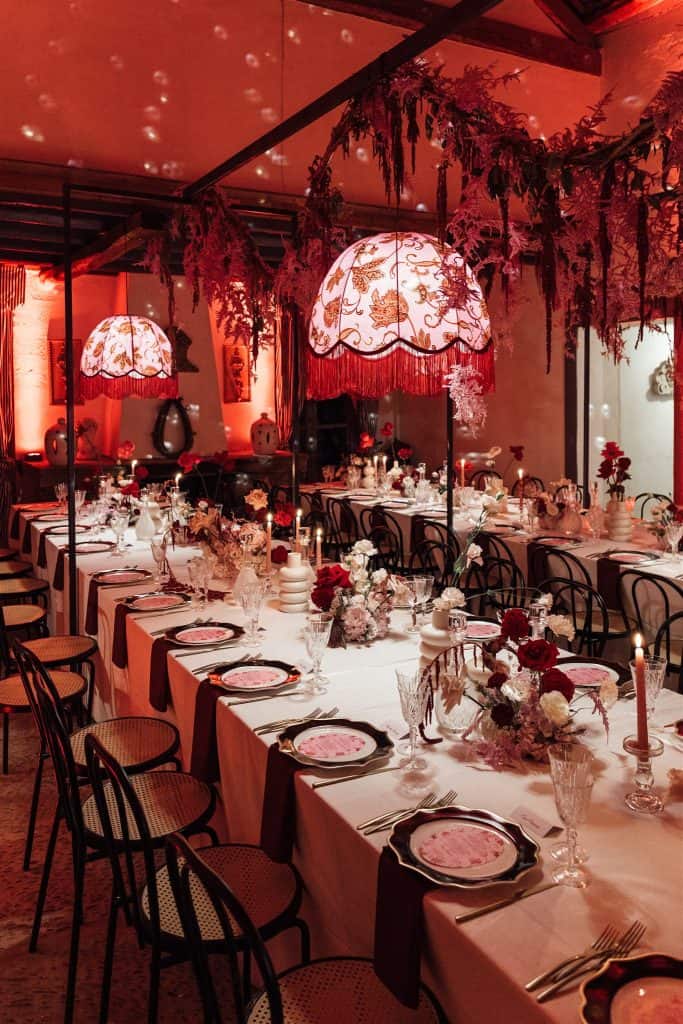 Lampadari decorativi con fiori e luci soffuse creano un'atmosfera elegante e romantica per matrimoni e eventi speciali, con tavoli splendidamente allestiti e dettagli raffinati per un ricevimento indi.