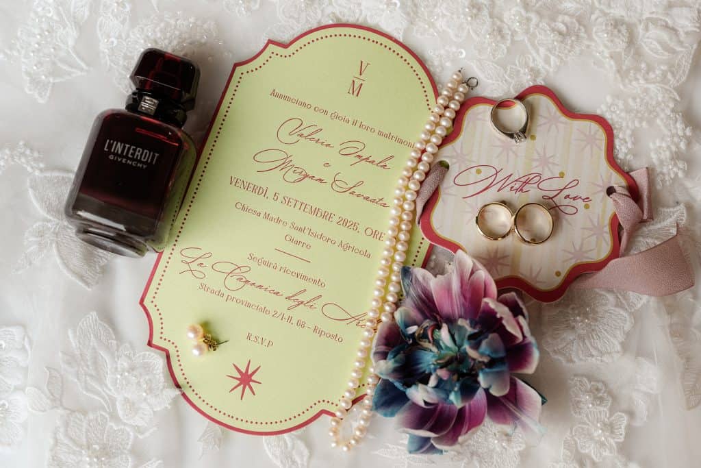 Profumo di nozze, invito elegante e dettagli di accessori per matrimonio, con fedi, perle e fiore decorativo, perfetti per un matrimonio raffinato organizzato da ChiaraB Events Wedding Planner.