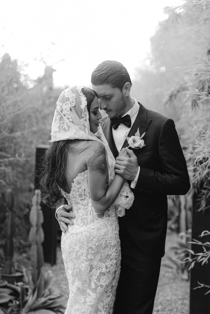 Un momento intimo tra sposi durante il matrimonio, con un abito da sposa in pizzo e un abito da uomo elegante, in un ambiente naturale e romantico. Perfetto esempio di wedding planning professionale.