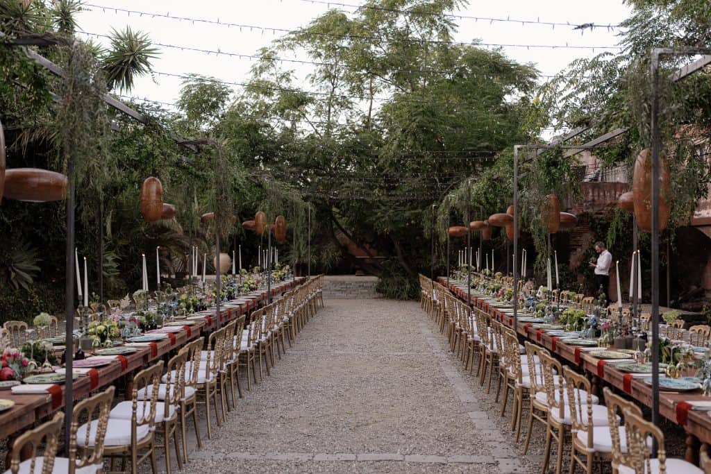 Elegante allestimento per matrimonio all'aperto con tavoli lunghi, decorazioni floreali e luci sospese, ideale per eventi romantici e sofisticati organizzati da ChiaraB Events Wedding Planner.