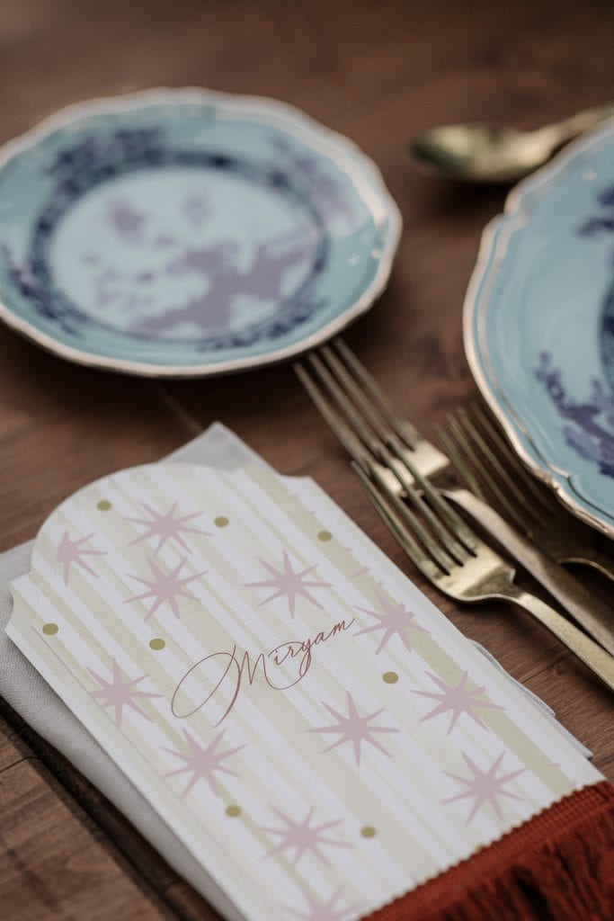 Piatti eleganti in porcellana blu con dettagli dorati, posate d'oro e un tovagliolo con nome personalizzato "Morgane" in stile sofisticato, perfetti per un matrimonio raffinato e ben organizzato.