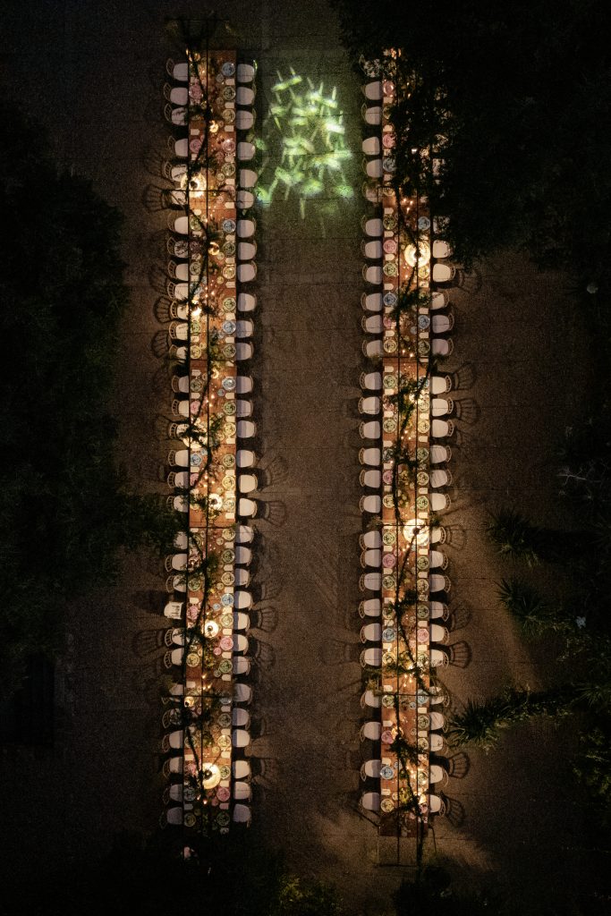 Tavolo per matrimonio all'aperto decorato con luci calde, fiori e candele, ambientazione romantica e elegante per un evento speciale. Perfetto per matrimoni e cerimonie all'aperto, con atmosfera intim.