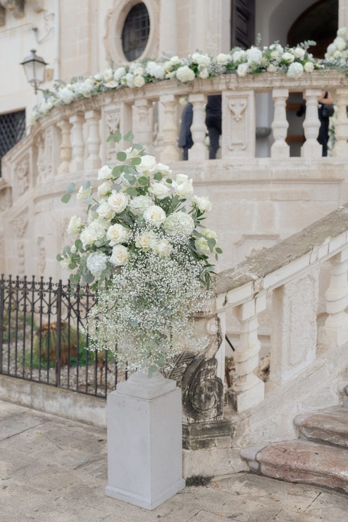 Elegante decorazione floreale con bouquet di rose bianche e fiori di baby's breath su un'installazione in pietra, perfetta per matrimoni e eventi di classe, creata da ChiaraB Events Wedding Planner.