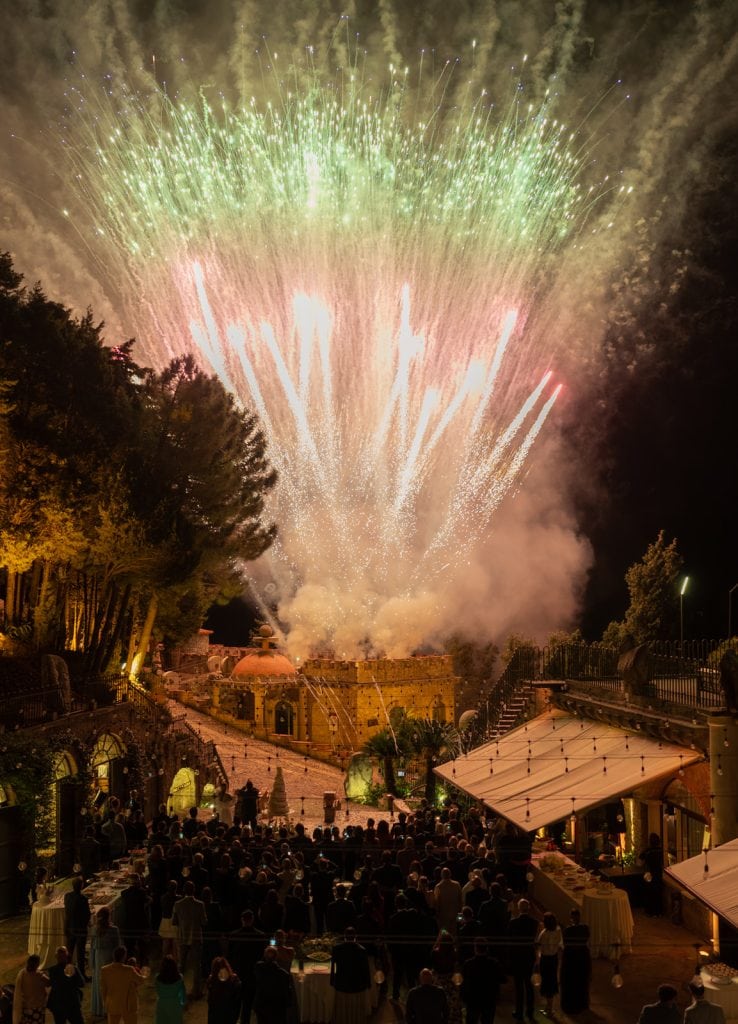 Fuochi d'artificio colorati durante un matrimonio all'aperto, creando un'atmosfera magica e indimenticabile per gli sposi e gli ospiti.