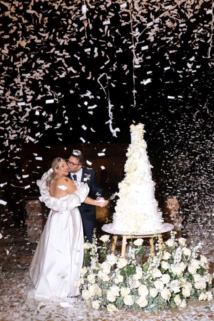 Tavolozza di colori eleganti con sposi felici che festeggiano il loro matrimonio con torta nuziale e decorazioni floreali. Atmosfera romantica e raffinata creata da ChiaraB Events Wedding Planner.