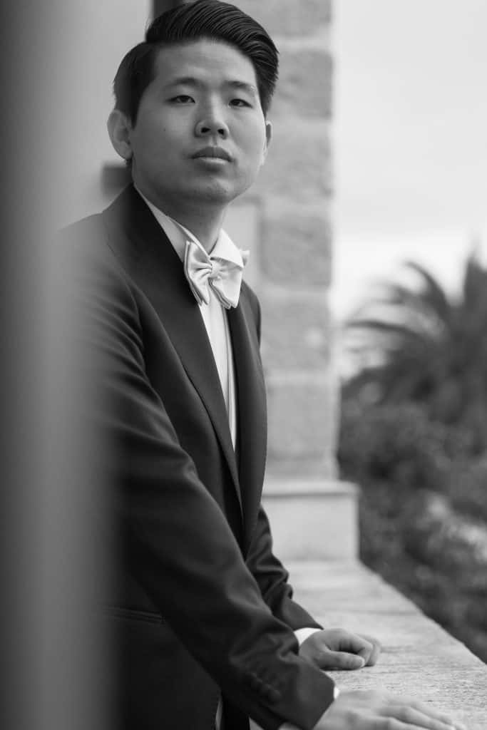 Elegante uomo in abito da cerimonia con cravatta, ritratto in un ambiente raffinato, perfetto per servizi di wedding planning e eventi di lusso.