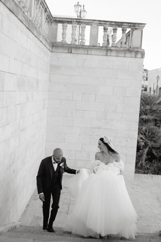 Alberto e Valeria durante il loro matrimonio, con Alberto in abito da sposo e Valeria in abito da sposa, in un'ambientazione romantica e raffinata.