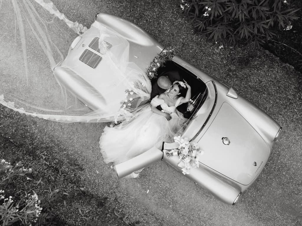 Spose in abito da matrimonio sedute in un'auto d'epoca, scena romantica e sofisticata, perfetta per servizi di wedding planning e allestimenti di matrimoni eleganti, catturando momenti speciali.