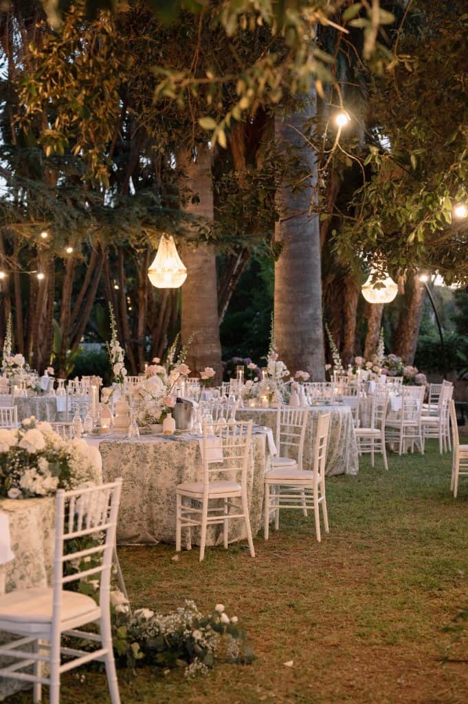 Allestimento matrimonio all'aperto con tavoli decorati e luci soffuse.