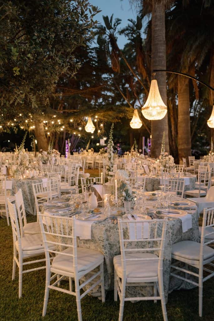 Allestimento matrimonio sulla spiaggia con tavoli eleganti, luci soffuse e decorazioni floreali, perfetto per un matrimonio romantico e raffinato all'aperto.