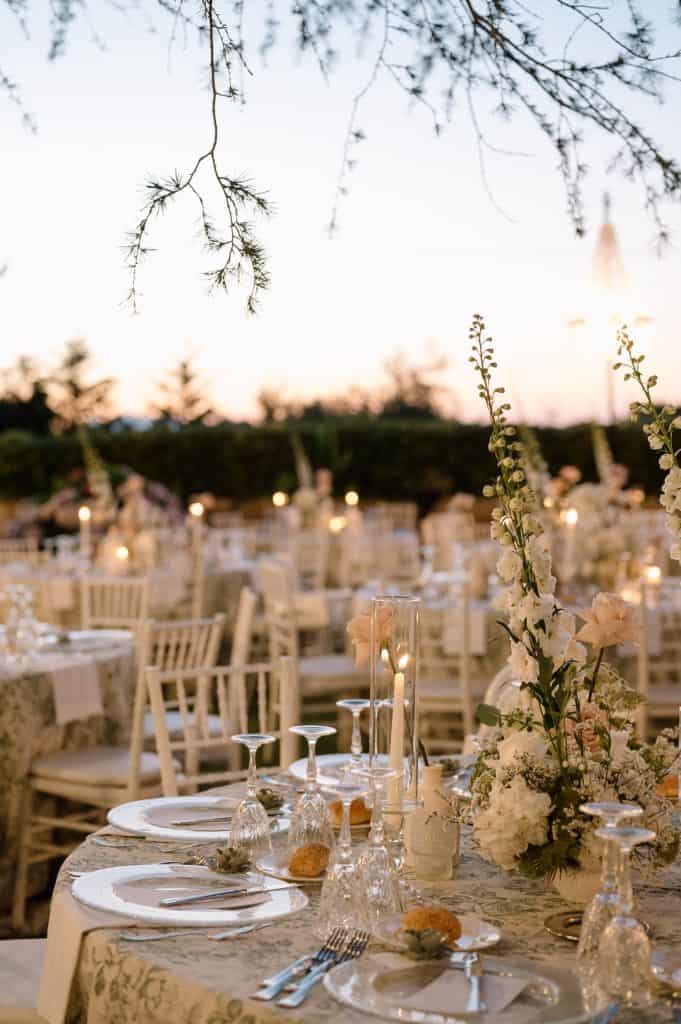 Allestimento matrimonio all'aperto con decorazioni floreali e luci soffuse, perfetto per un matrimonio romantico e raffinato.