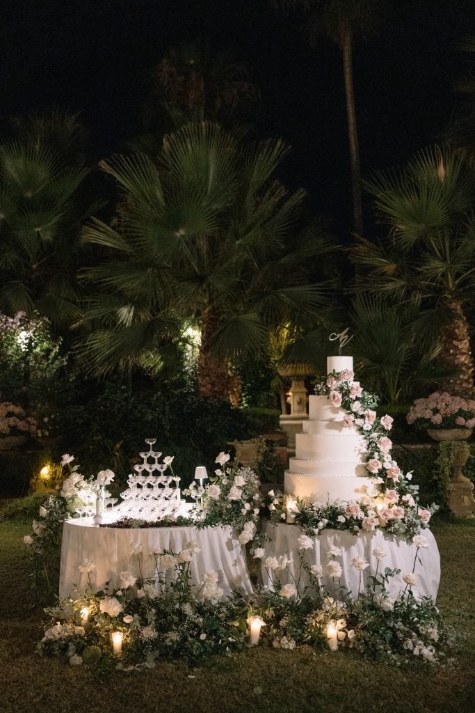 Torta nuziale elegante con decorazioni floreali e allestimento romantico all'aperto, perfetto per matrimoni esclusivi.