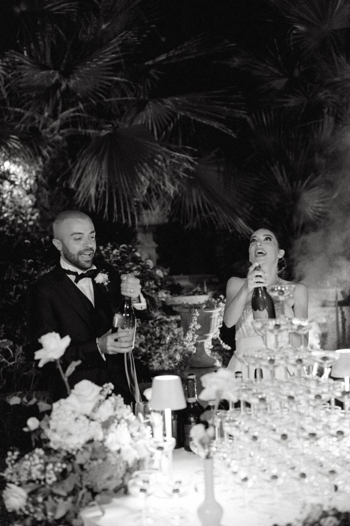 Coppia di sposi Alberto e Valeria durante il ricevimento di nozze, con decorazioni floreali e brindisi, in un'atmosfera elegante e festosa.