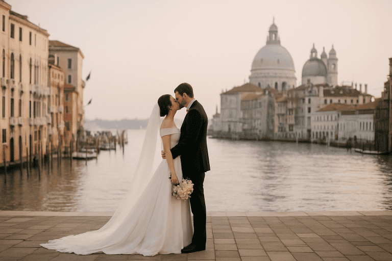 Coppia di sposi che si bacia a Venezia, con la Basilica di Santa Maria della Salute sullo sfondo, durante un matrimonio intimo e senza folla.